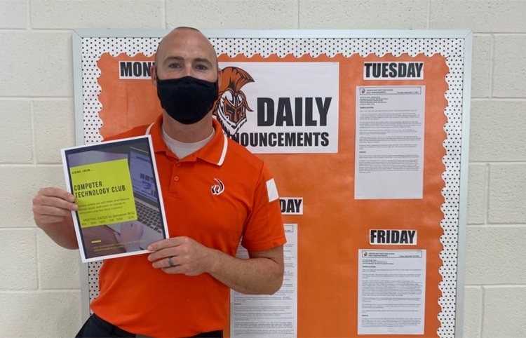 club sponsor holding a flyer in front of the announcements